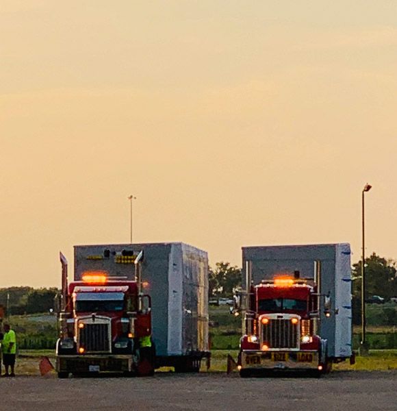 Two semi trucks are parked next to each other in a parking lot.