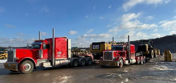 Two red semi trucks are parked next to each other in a parking lot.