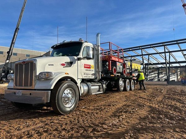 A large white semi truck is parked in a dirt field.