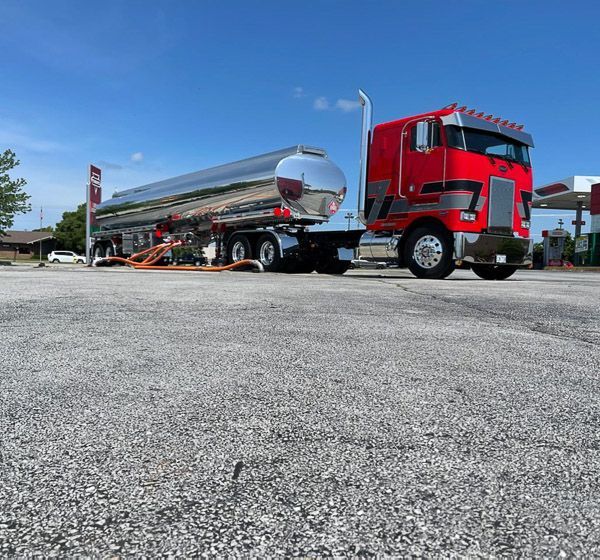 A red semi truck is parked at a gas station