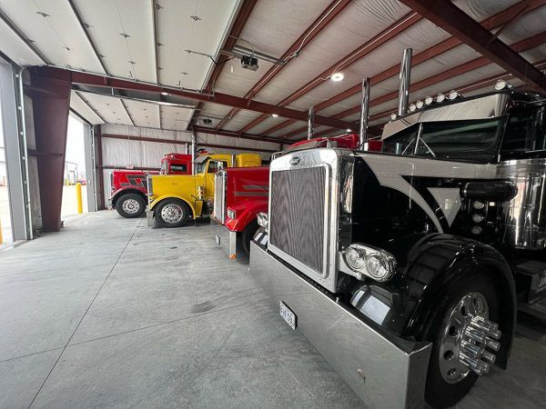 A row of semi trucks are parked in a garage