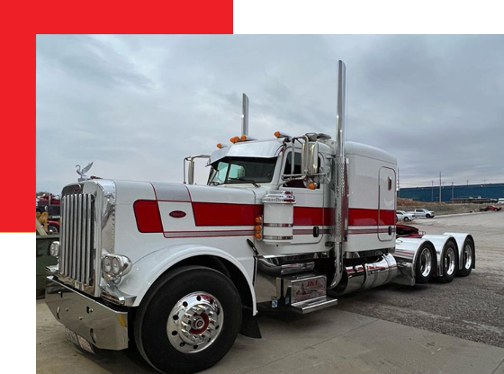 A red and white semi truck is parked in a parking lot