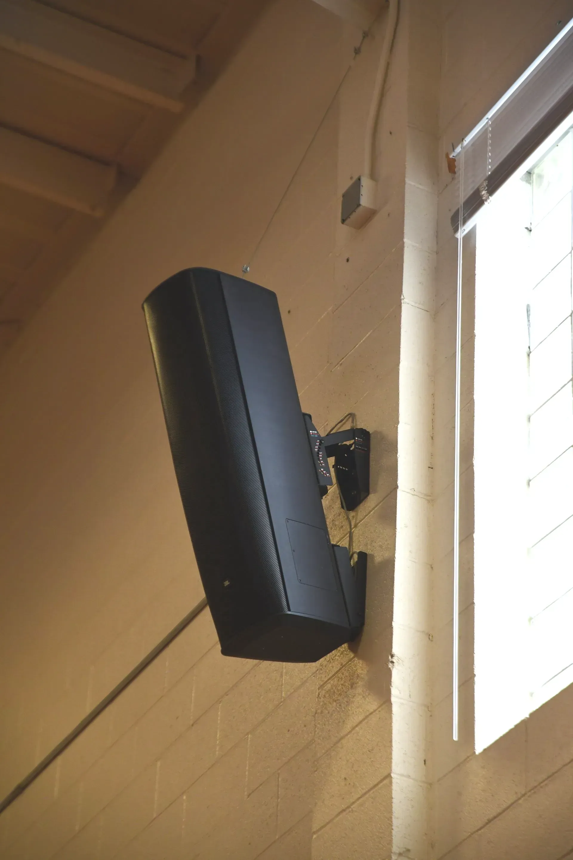 A speaker mounted on a wall next to a window