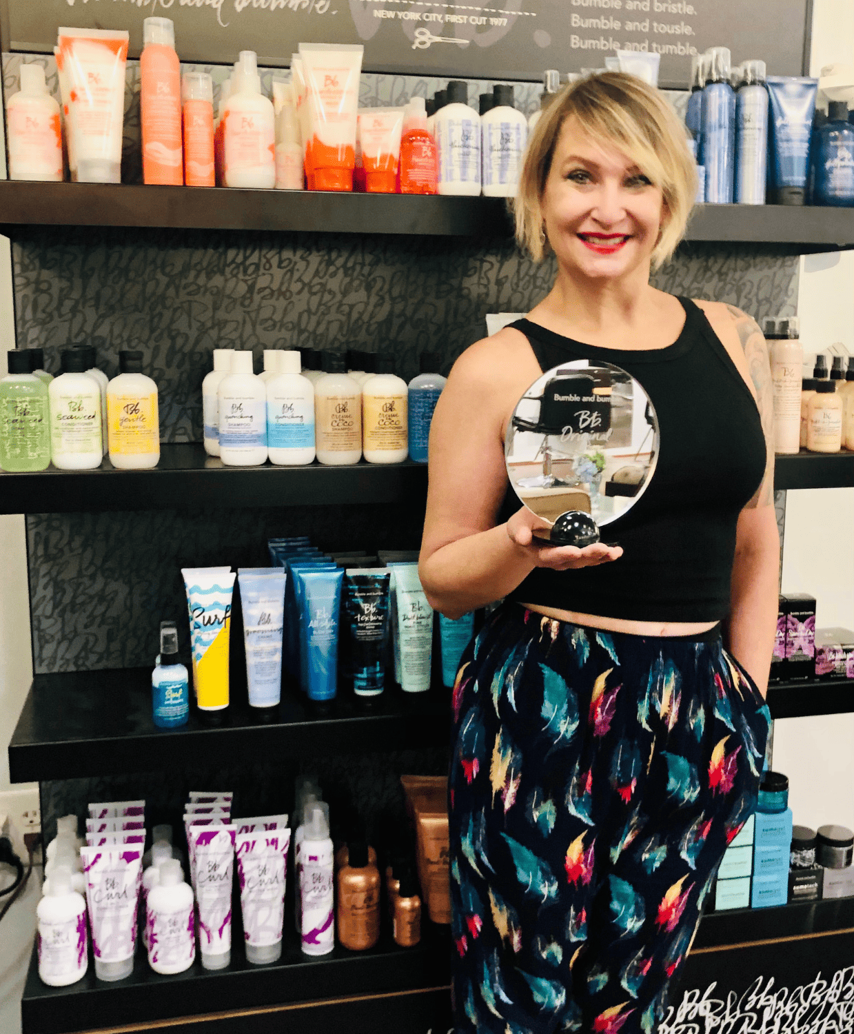 A woman is holding a trophy in front of a shelf full of hair products
