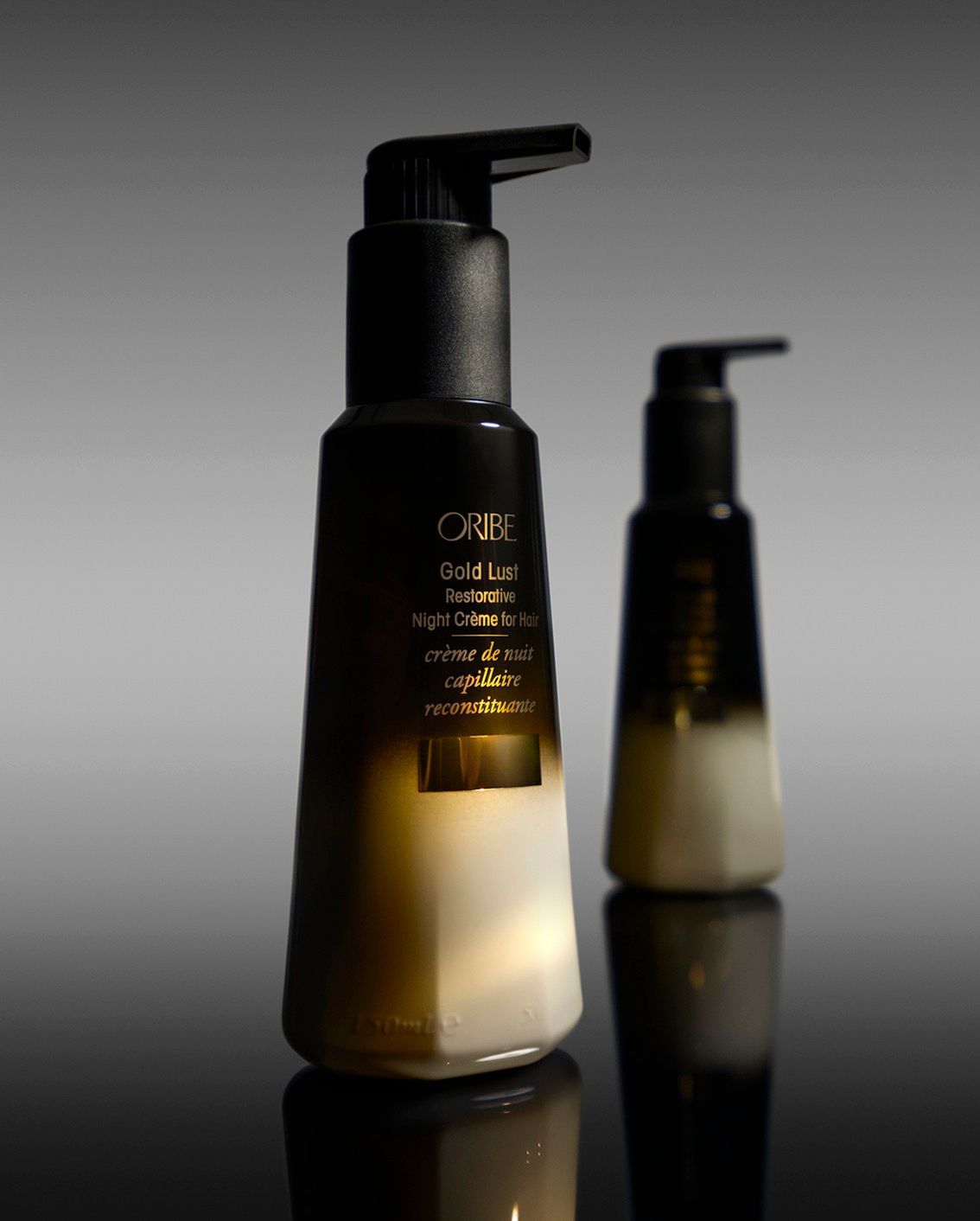 Two bottles of oribe hair products are sitting next to each other on a table.
