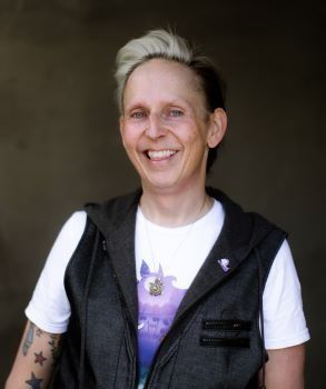 A woman wearing a vest and a white shirt is smiling