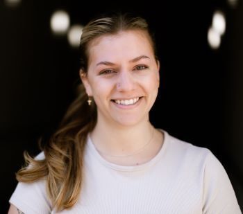 A woman in a white shirt is smiling for the camera.