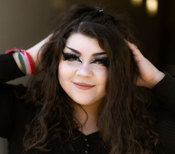 A woman with long hair is wearing a black shirt and holding her hair.