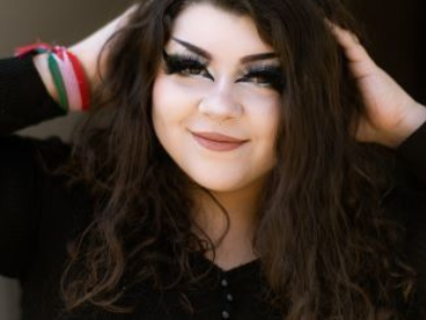 A woman with long hair is wearing a black shirt and holding her hair.