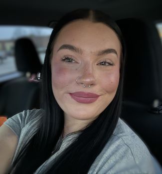 A woman is taking a selfie in the back seat of a car.