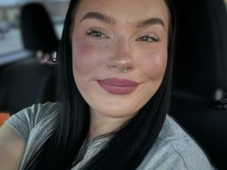 A woman is taking a selfie in the back seat of a car.