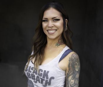 A woman wearing a tank top that says black sabbath is smiling.