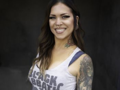 A woman wearing a tank top that says black sabbath is smiling.