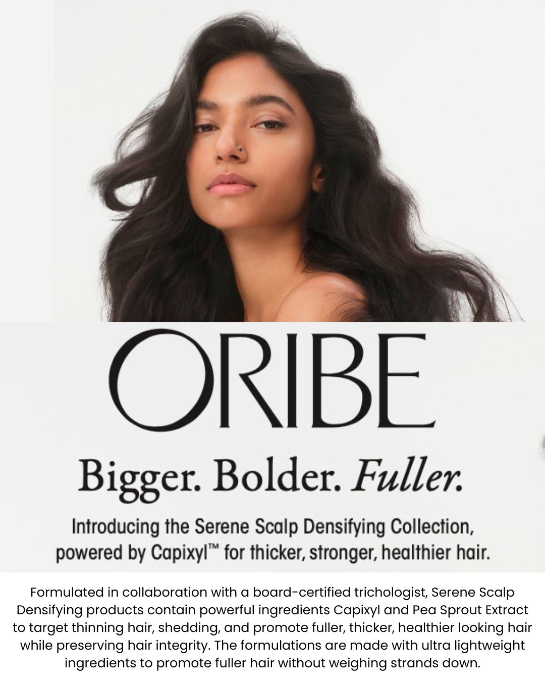 A woman is standing in front of a sign that says oribe bigger , bolder , fuller.