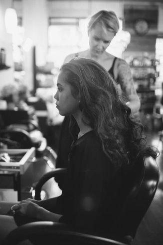 A woman is getting her hair done at a salon in a black and white photo.