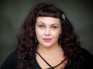 A woman with curly hair is wearing a black shirt and earrings.