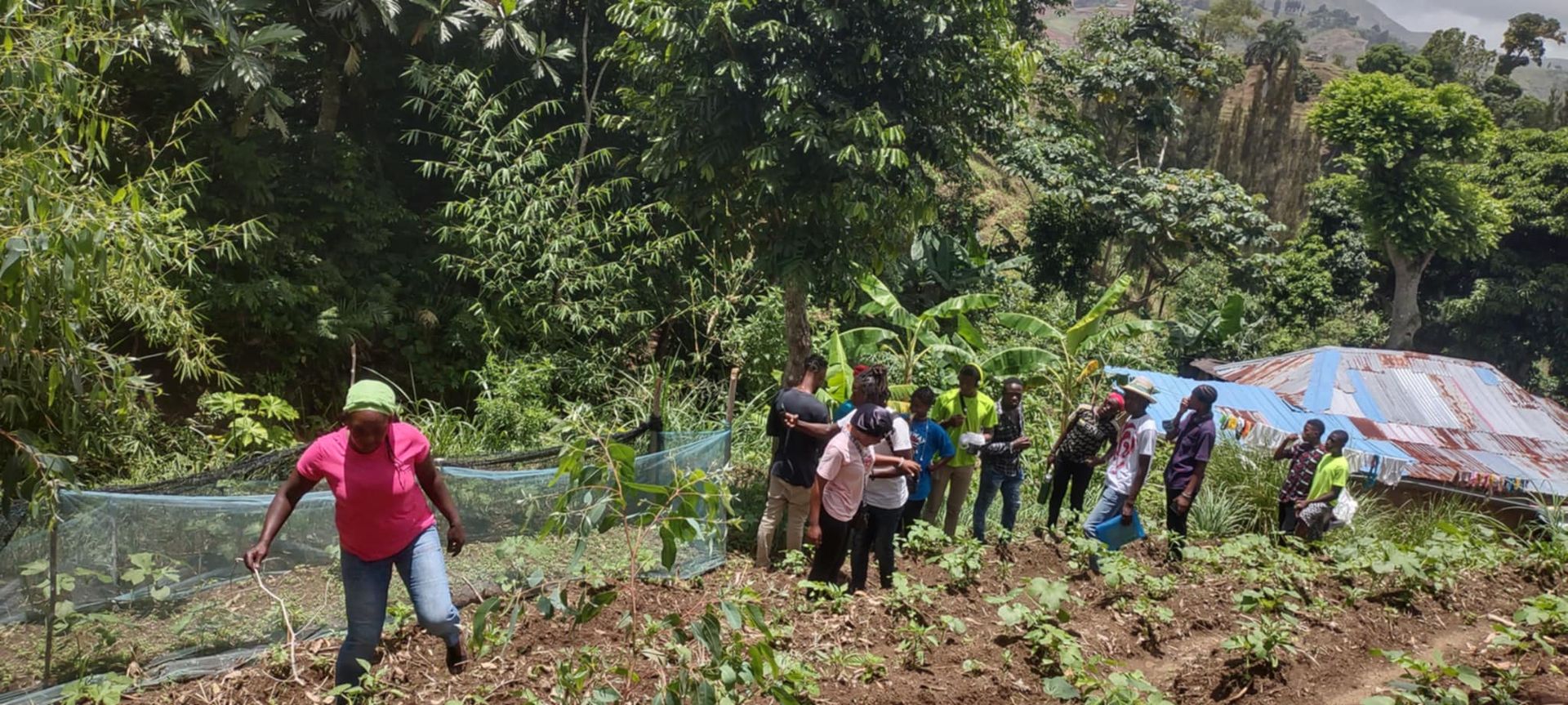 A group of young people and a teacher walking in a garden.