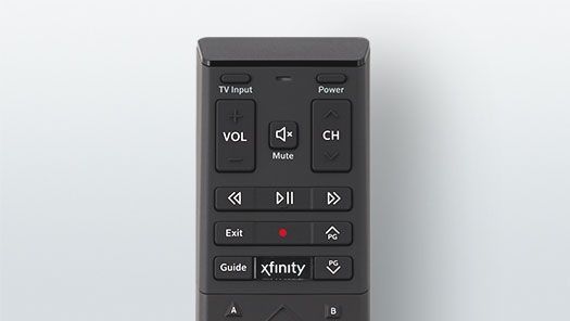 A black remote control is sitting on a white surface.