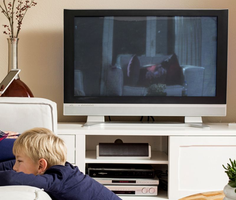 A boy laying on a couch watching a tv