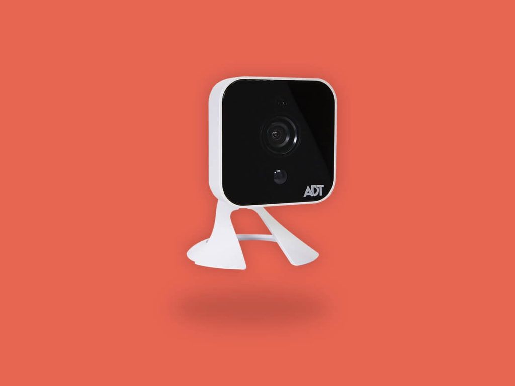 A security camera is sitting on a stand on a red background.