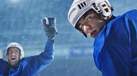 Two hockey players are standing on the ice with their arms in the air.