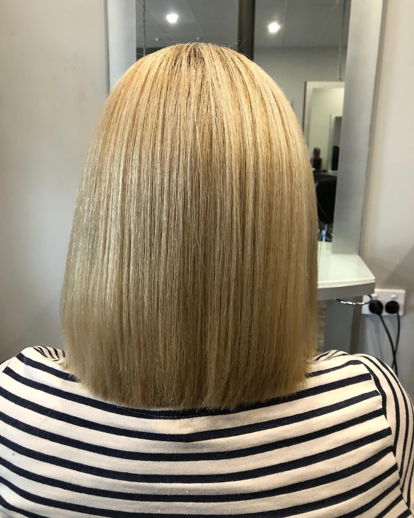 The back of a woman's head with blonde hair and a striped shirt — Carlee Hair Design In Anula, NT