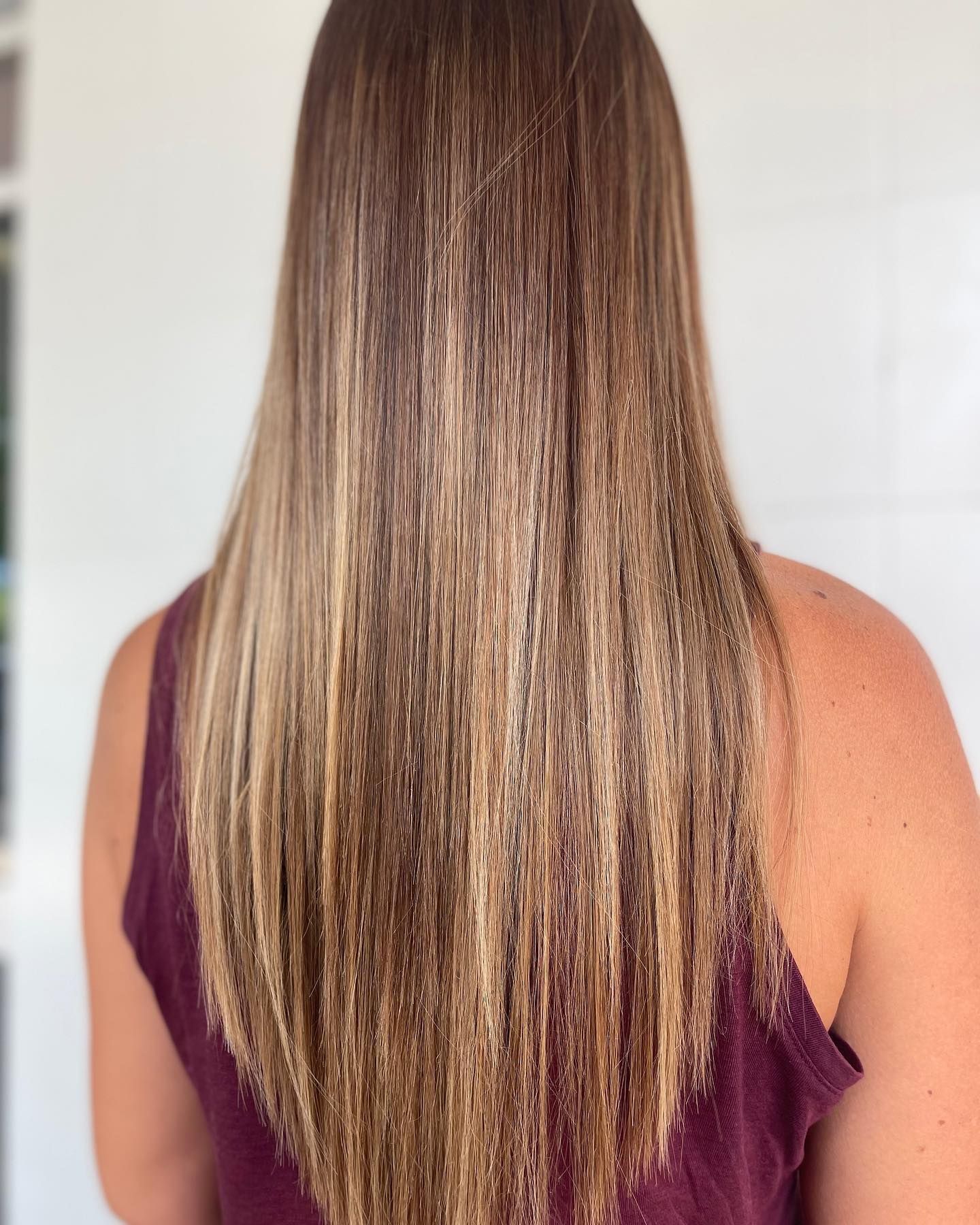 A woman with long hair is wearing a purple tank top — Carlee Hair Design In Anula, NT