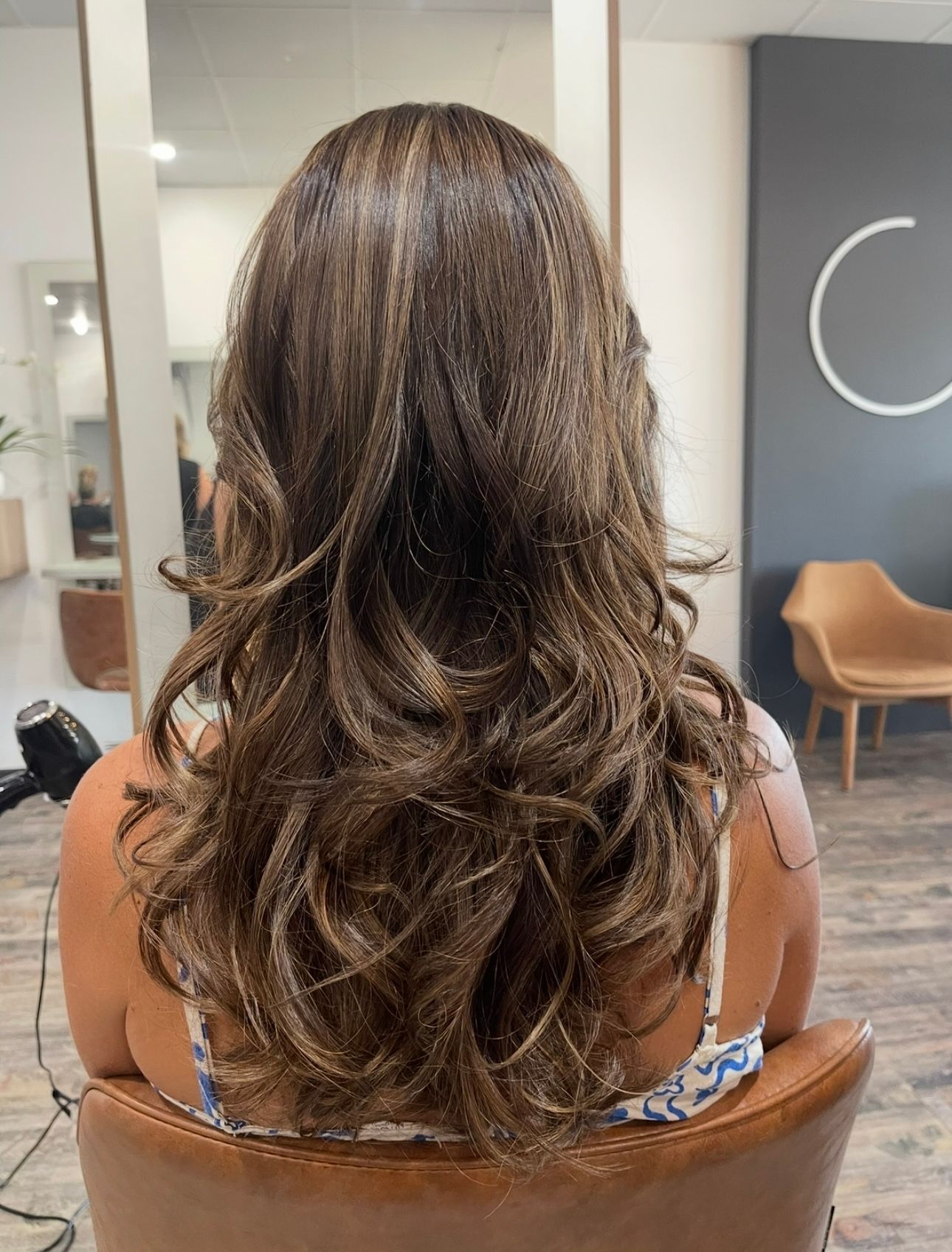 A woman in a salon with brown curly hair — Carlee Hair Design In Anula, NT