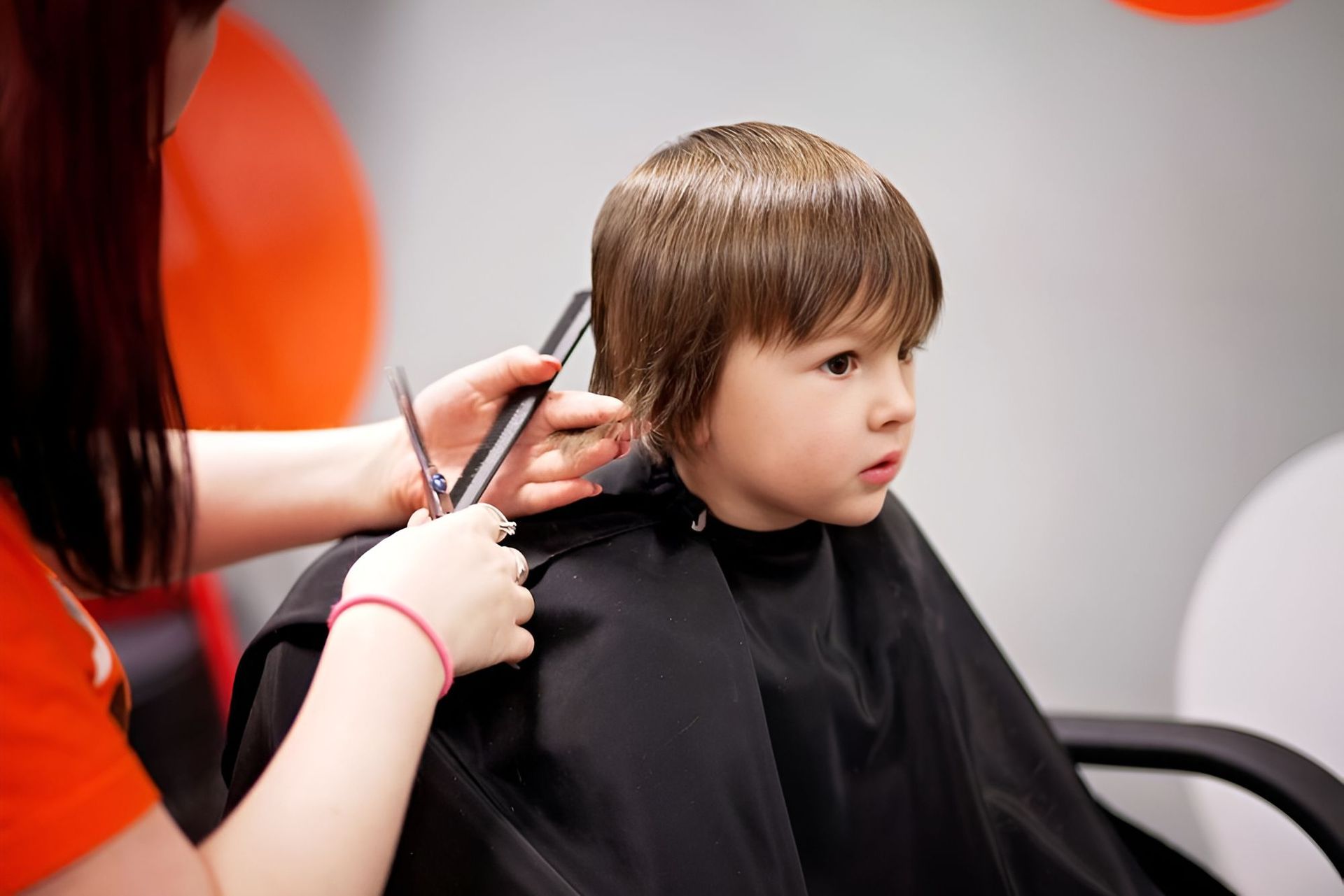 A Little Boy Is Getting His Hair Cut By A Woman At A Hair Salon — Carlee Hair Design In Anula, NT