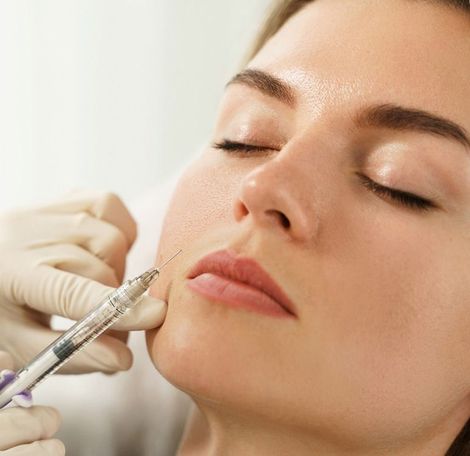 A woman wearing blue gloves is holding a syringe in front of a patient.