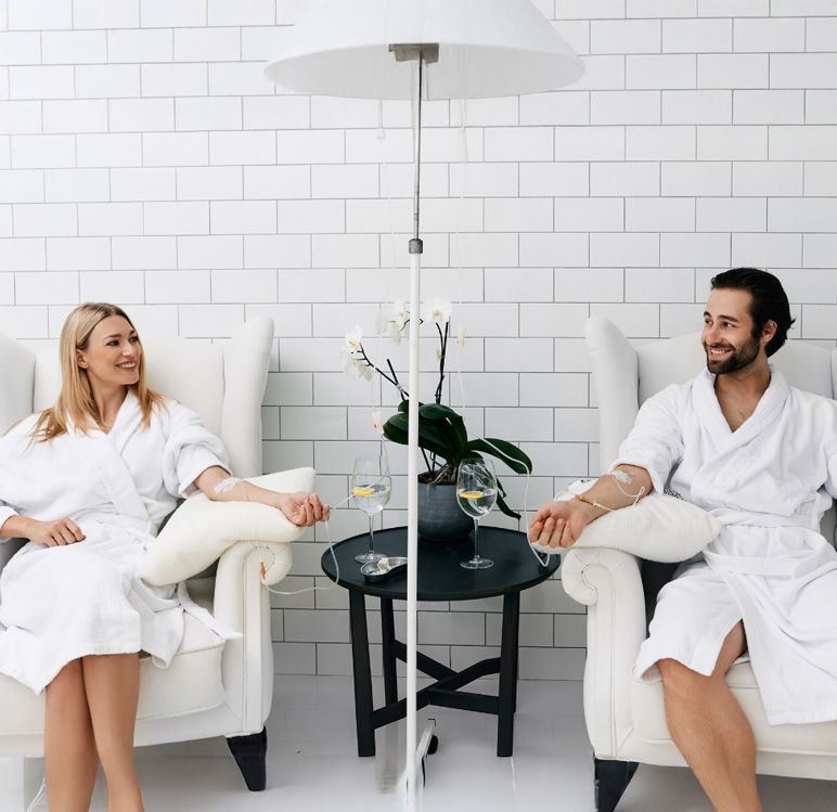 A man and a woman are sitting in chairs talking to each other.