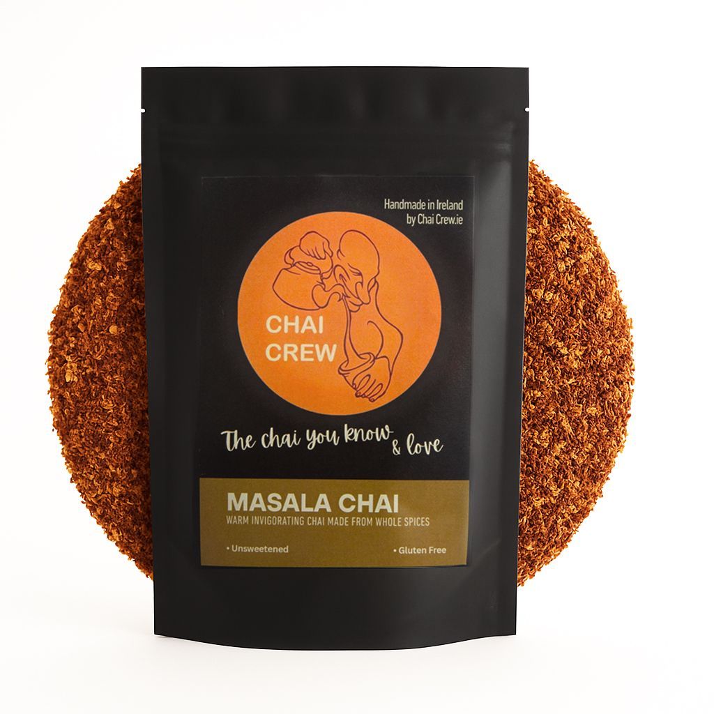 Black pouch of Masala Chai tea with orange logo and text, surrounded by loose tea.