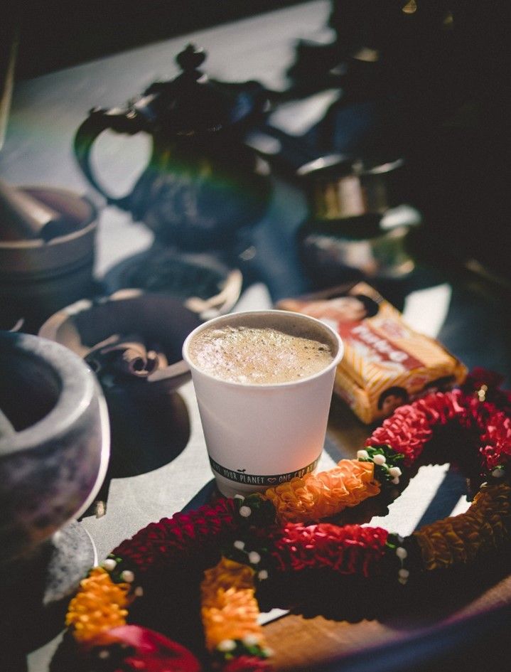 Cup of coffee, garland, and teaware on a tray; brightly lit, with warm tones.