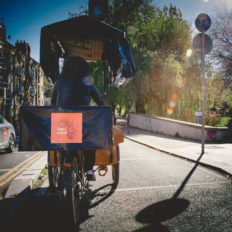 A person rides a yellow cargo bike with a black canopy on a sunny street.