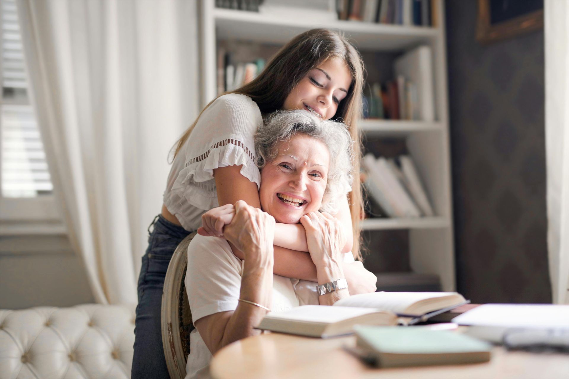 A young girl is hugging an older woman in a living room.