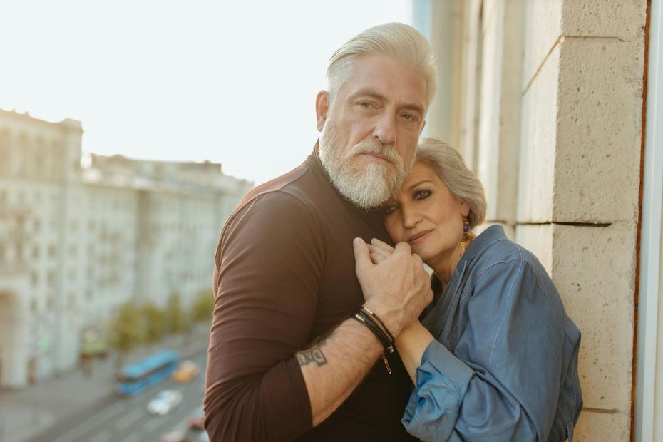 A man and a woman are hugging each other on a balcony.