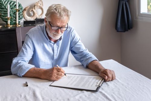 Old man is signing a contract