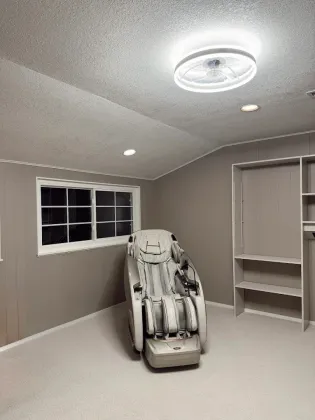 Room with massage chair, window, recessed lights, closet shelving, and ceiling fan. Gray walls, light carpet.