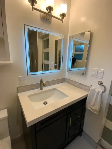 Bathroom with a vanity, sink, mirrors, and a towel.