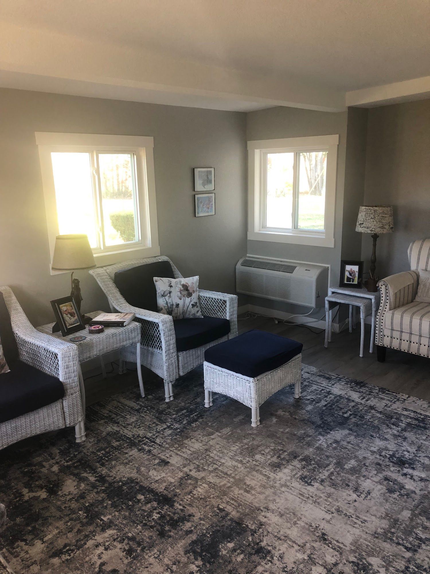 Living room with white wicker furniture, navy cushions, and a patterned rug.