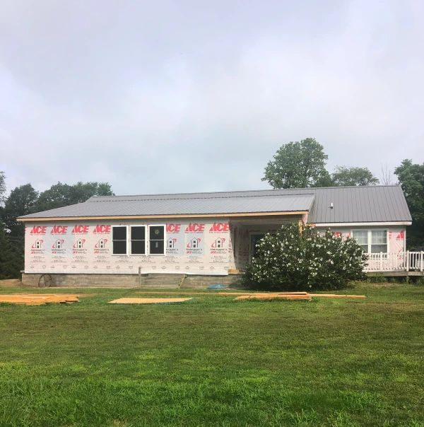 Man inspecting ceiling damage with a tool, holding a clipboard, in a room with debris.