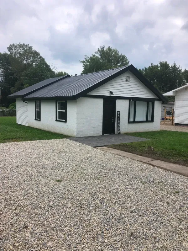 Living room with white wicker furniture, navy cushions, and a patterned rug.