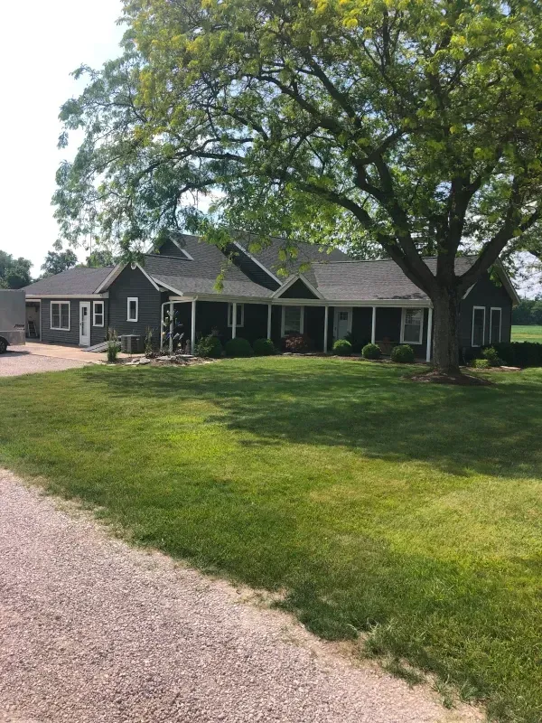 A room with gray walls, a sliding barn door, two white wicker chairs, and a blue and gray rug.