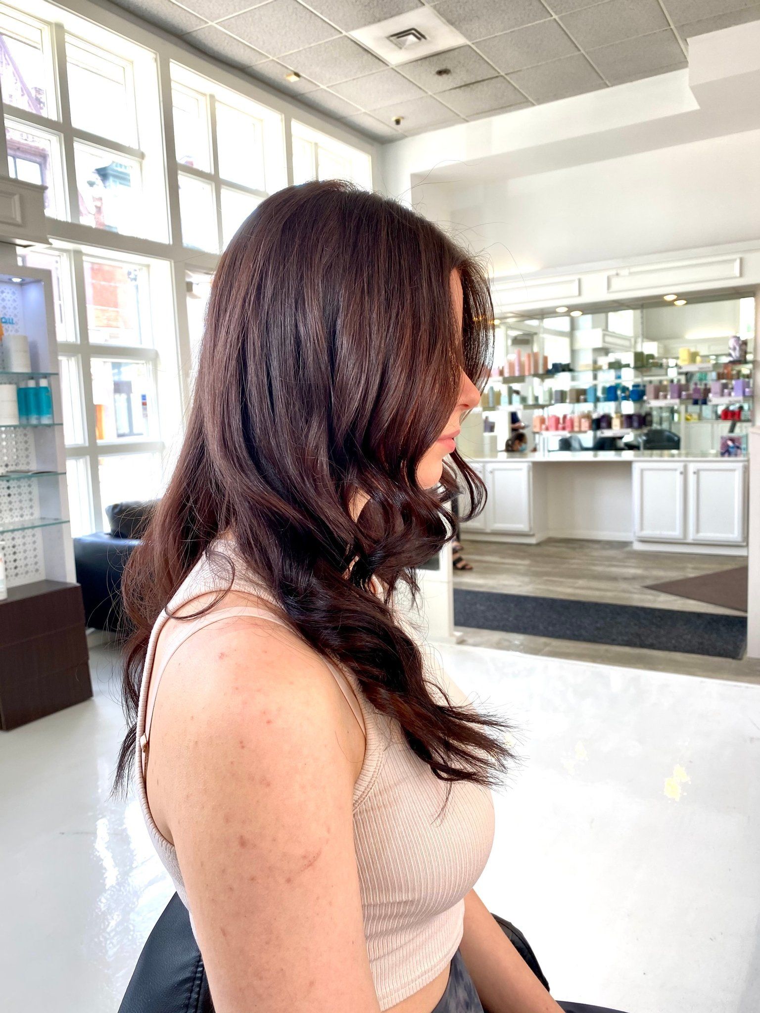 A woman with long brown hair is sitting in a chair in a salon.