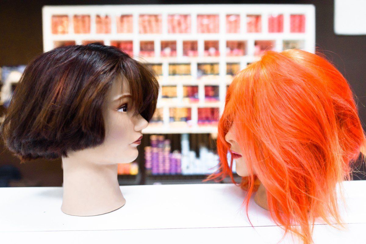 Two mannequin heads with wigs on them are sitting next to each other on a table.