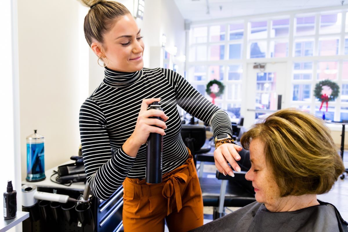 A woman is getting her hair cut by a hairdresser in a salon.
