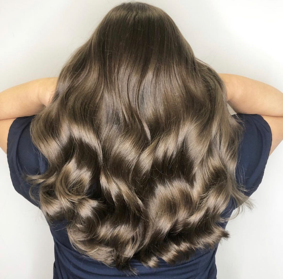 A woman with long brown hair is wearing a blue shirt