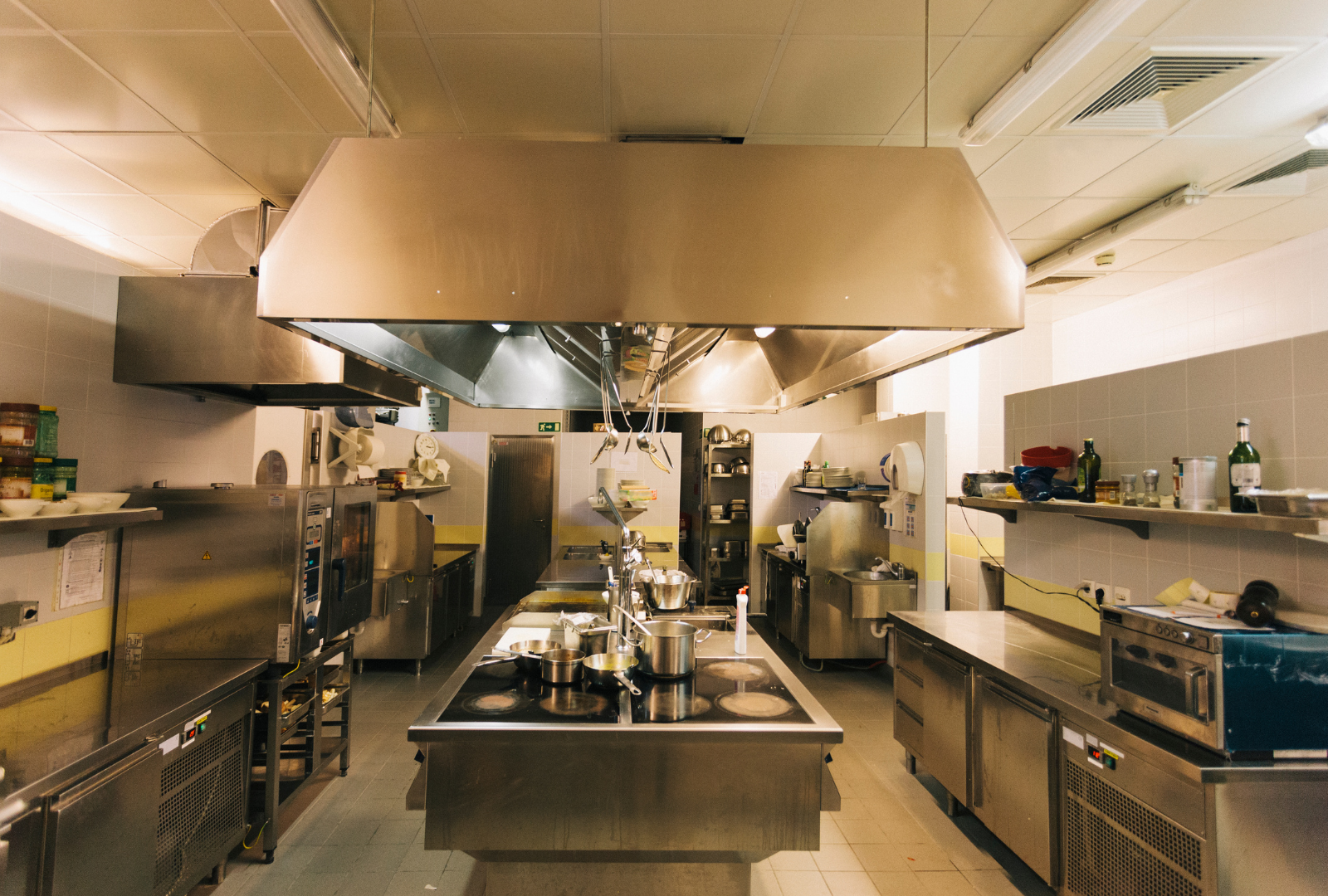 Commercial kitchen with stainless steel appliances and ventilation hood.