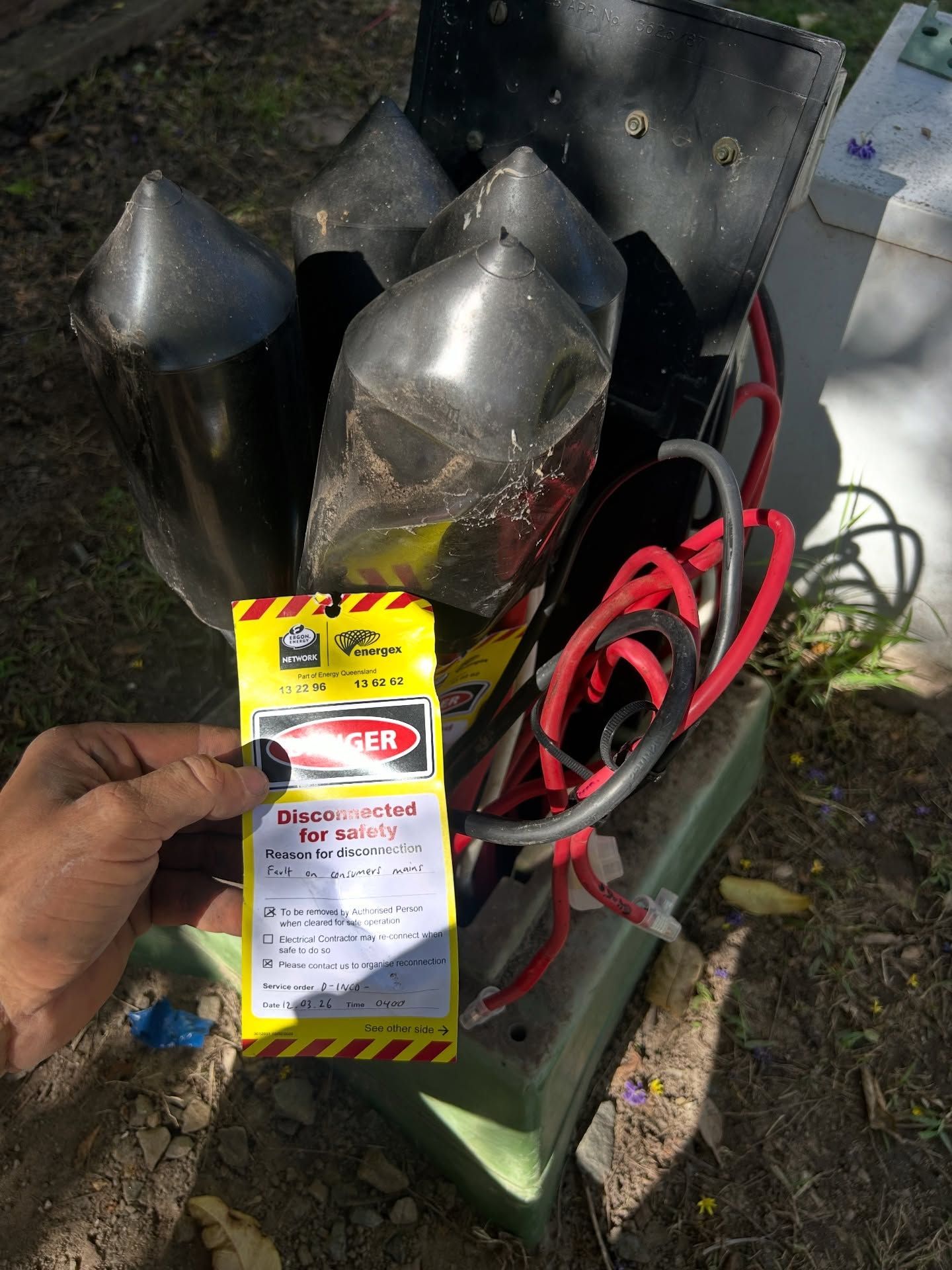 Hand holding a box of bug spray in front of several black metal chimneys or vents outdoors— BTM Electrical & Air in Burleigh Waters, QLD