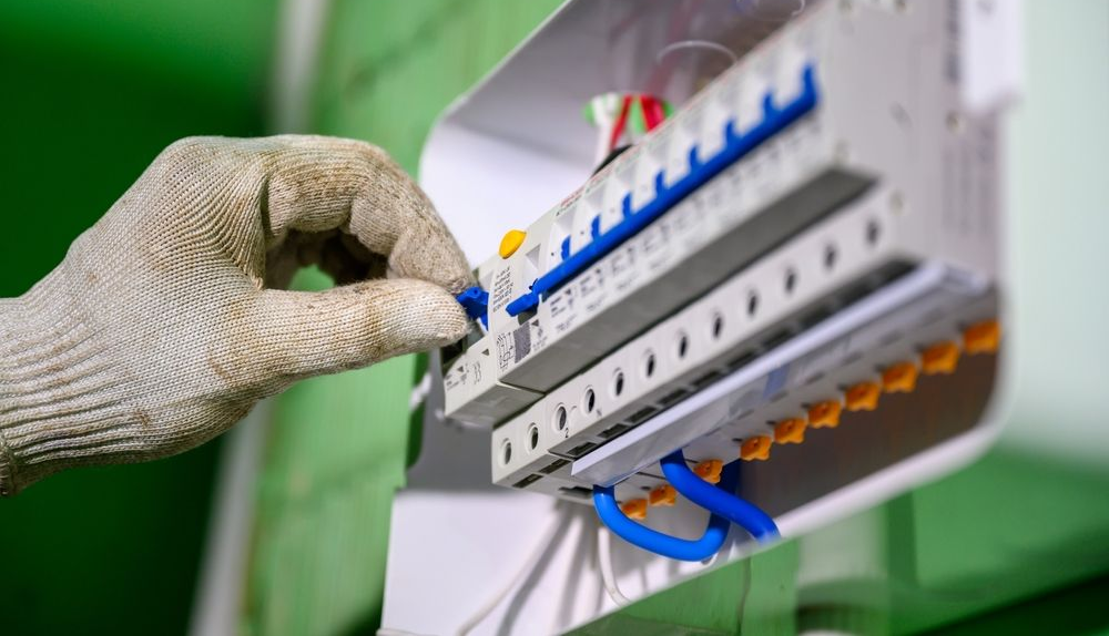 A Gloved Hand Flips a Blue Circuit Breaker Switch — BTM Electrical & Air in Burleigh Waters, QLD